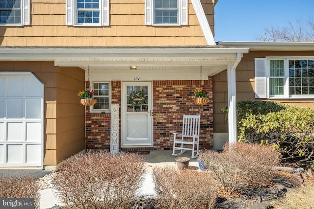 entrance to property featuring covered porch and brick siding