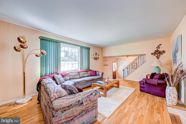 living room with stairs, light wood finished floors, and baseboards