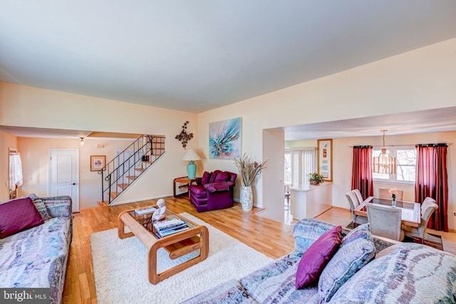 living room with a chandelier, stairway, and wood finished floors