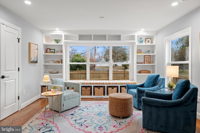 living area with baseboards, built in shelves, wood finished floors, and recessed lighting