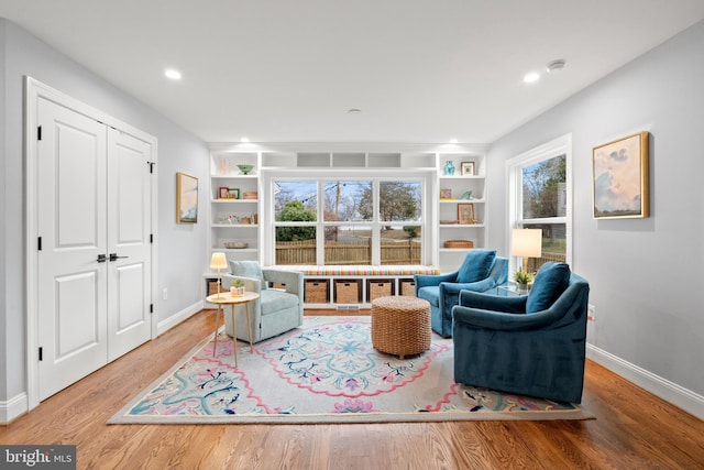 sitting room with built in shelves, baseboards, wood finished floors, and recessed lighting