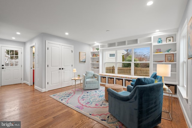 sitting room featuring built in shelves, recessed lighting, baseboards, and wood finished floors