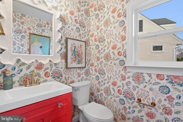 bathroom with vanity, toilet, and wallpapered walls