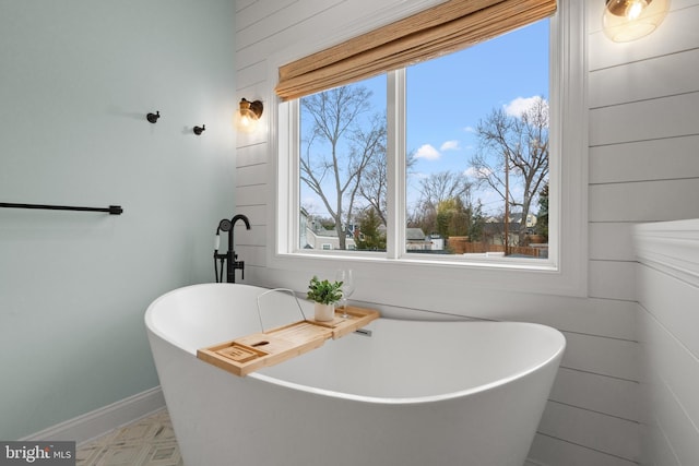 full bath featuring a freestanding tub and baseboards