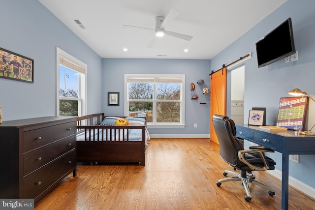 bedroom featuring light wood finished floors, recessed lighting, visible vents, a barn door, and baseboards