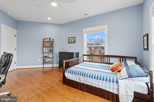 bedroom with baseboards, visible vents, ceiling fan, and wood finished floors