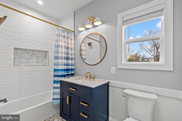 full bath featuring toilet, a wainscoted wall, shower / bathtub combination with curtain, and vanity