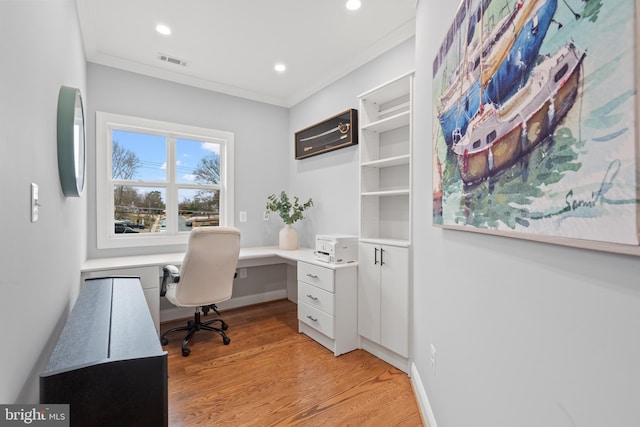 office with baseboards, light wood-type flooring, visible vents, and crown molding