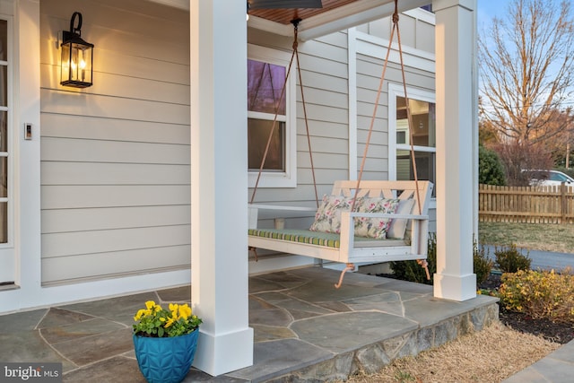 entrance to property with covered porch and fence