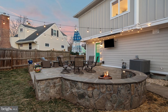 view of patio / terrace with an outdoor fire pit, fence, and central air condition unit