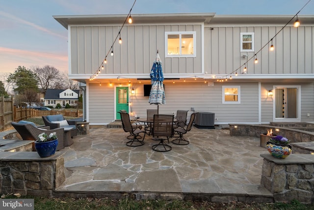 back of property featuring board and batten siding, fence, outdoor dining area, a patio area, and central AC