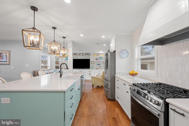 kitchen with custom range hood, appliances with stainless steel finishes, open floor plan, wood finished floors, and white cabinetry