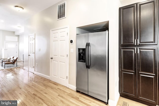 kitchen featuring visible vents, light wood-style flooring, dark brown cabinetry, stainless steel fridge, and baseboards