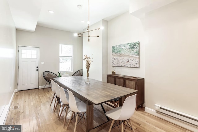 dining space with light wood-style floors, a baseboard radiator, baseboards, and an inviting chandelier