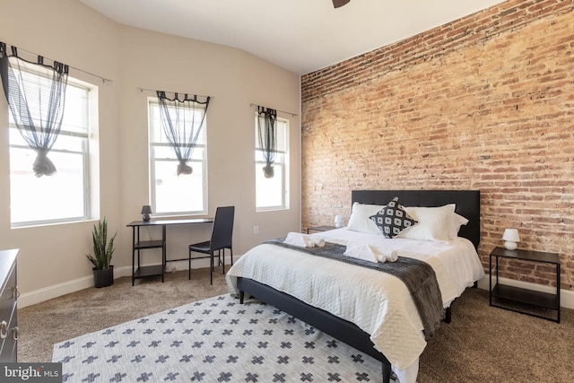 carpeted bedroom with vaulted ceiling, brick wall, and baseboards