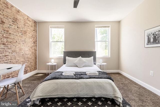 carpeted bedroom with brick wall, baseboards, and a ceiling fan