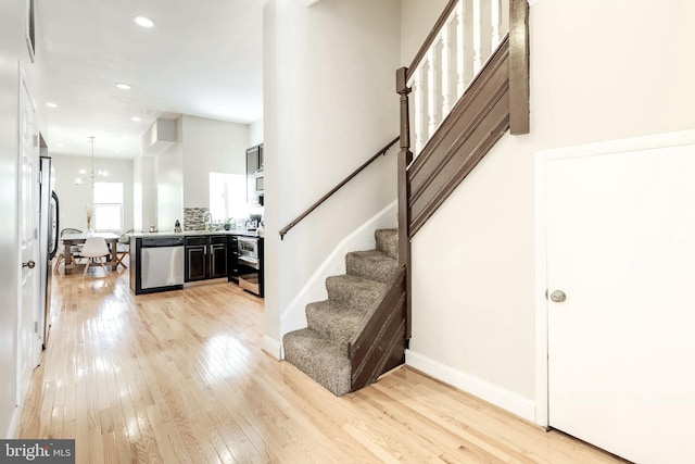 entryway featuring recessed lighting, baseboards, stairs, light wood-type flooring, and an inviting chandelier