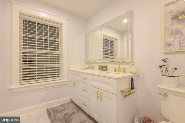 bathroom featuring double vanity, baseboards, toilet, and a sink