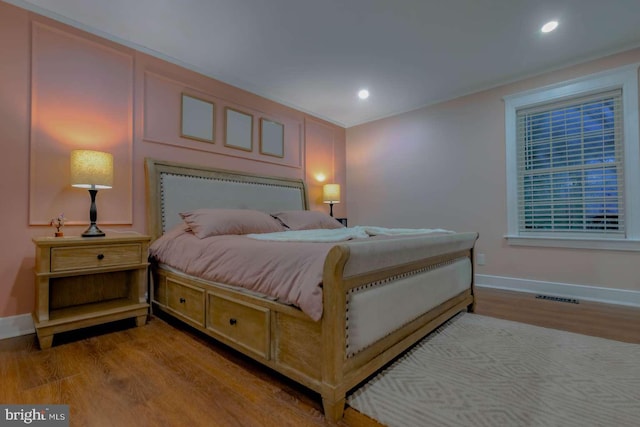 bedroom with baseboards, visible vents, wood finished floors, and recessed lighting