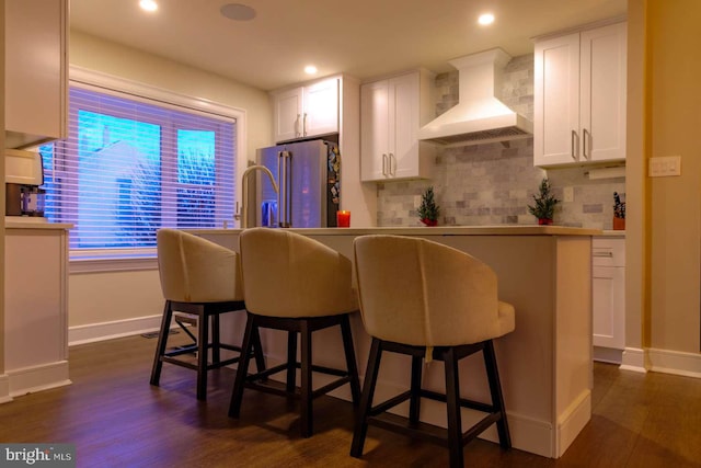 kitchen with high quality fridge, dark wood finished floors, white cabinets, and custom range hood