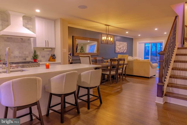 bar featuring tasteful backsplash, custom range hood, ornamental molding, wood finished floors, and stairs