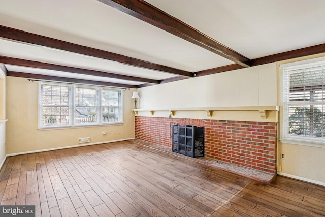 unfurnished living room with wood-type flooring, baseboards, a fireplace, and beam ceiling