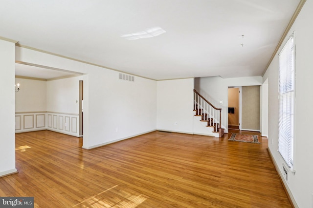 interior space with wood finished floors, visible vents, crown molding, and stairs