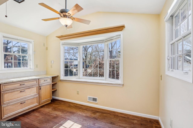 unfurnished dining area featuring dark wood-style floors, lofted ceiling, visible vents, ceiling fan, and baseboards