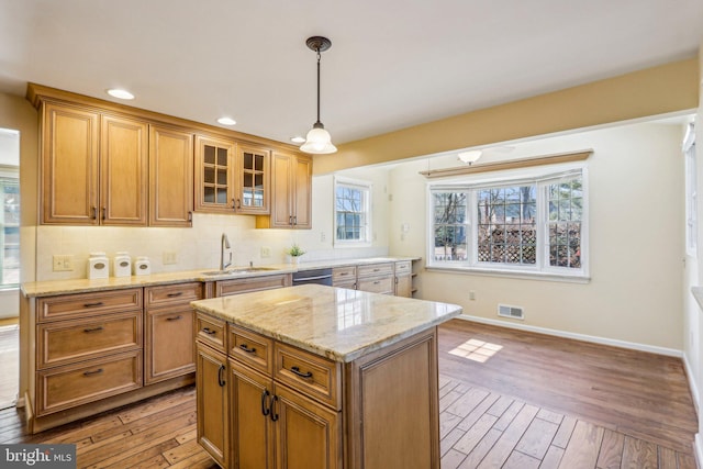 kitchen with backsplash, a sink, visible vents, and light wood-style floors