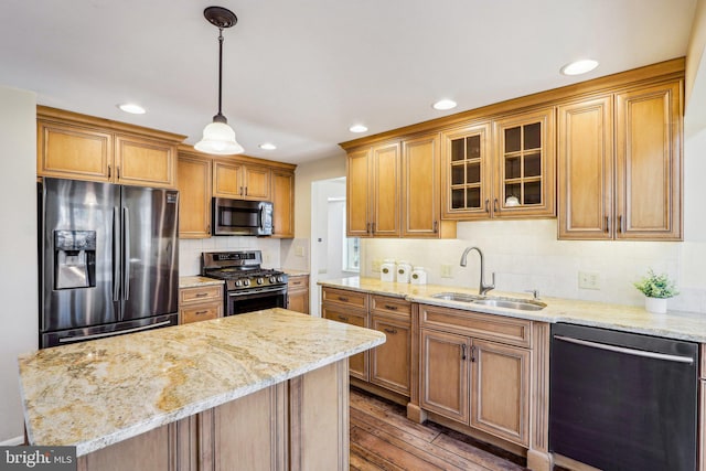 kitchen with appliances with stainless steel finishes, brown cabinets, a sink, and wood finished floors