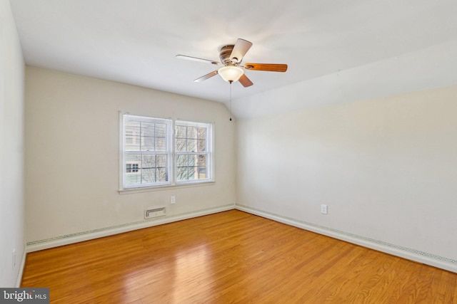 unfurnished room with lofted ceiling, ceiling fan, visible vents, and wood finished floors