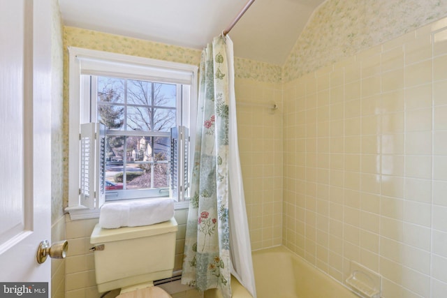 full bath with shower / tub combo, vaulted ceiling, and wallpapered walls