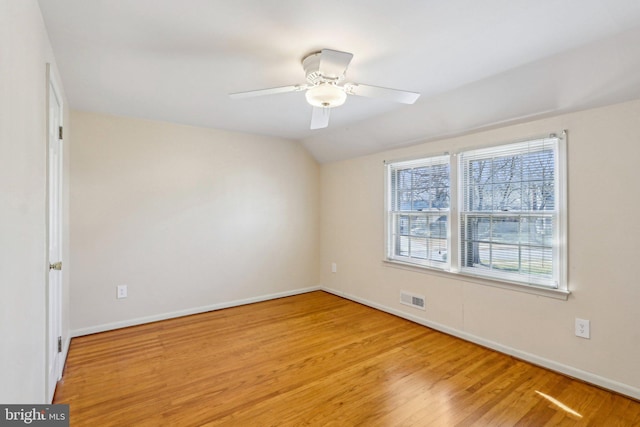 spare room with visible vents, baseboards, vaulted ceiling, a ceiling fan, and light wood-type flooring