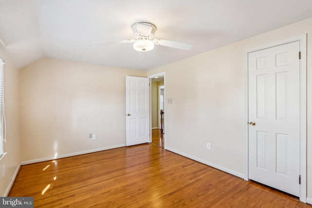 unfurnished bedroom with light wood-style floors, vaulted ceiling, and baseboards