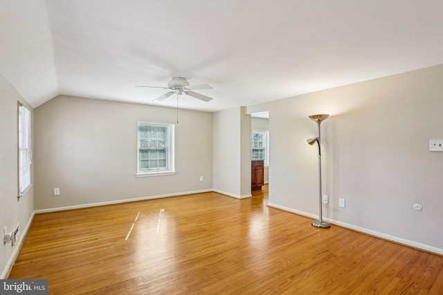 unfurnished room with ceiling fan, vaulted ceiling, light wood-style flooring, and baseboards