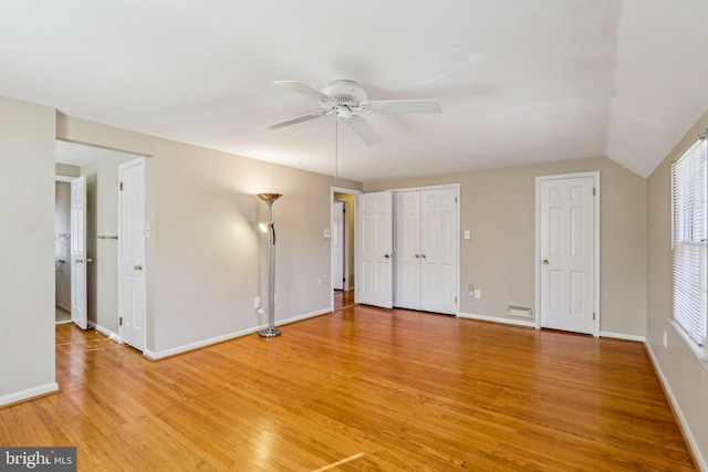 unfurnished bedroom featuring baseboards, ceiling fan, vaulted ceiling, and light wood-style floors