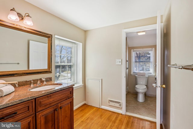 bathroom featuring baseboards, vanity, toilet, and wood finished floors