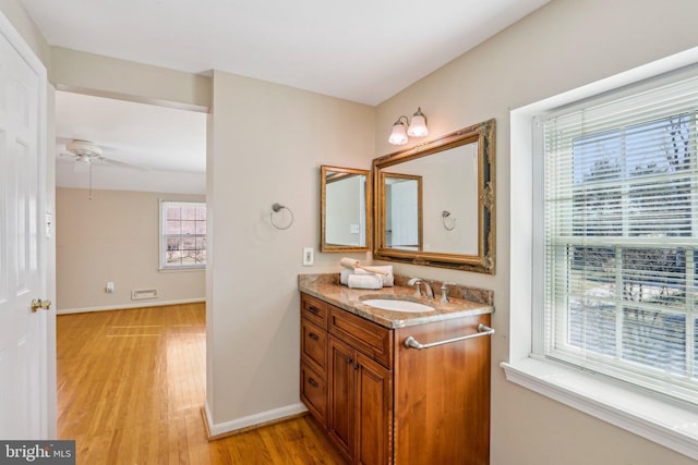 bathroom with ceiling fan, baseboards, wood finished floors, and vanity