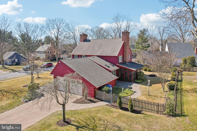 view of front of home featuring driveway, a fenced front yard, a chimney, and a front yard