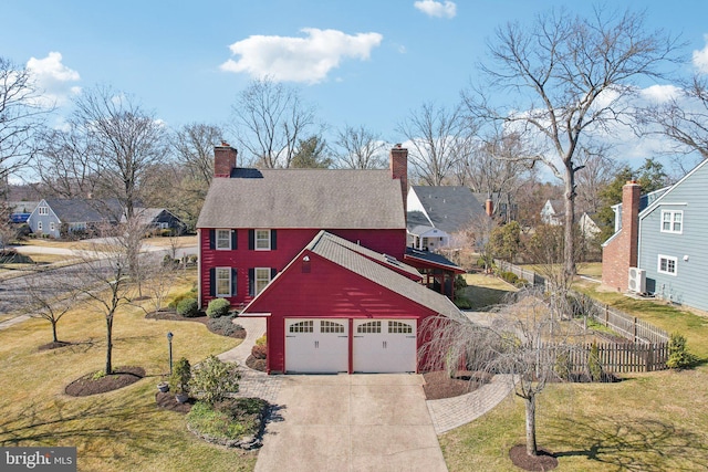 view of front facade featuring a garage, driveway, a front lawn, and fence