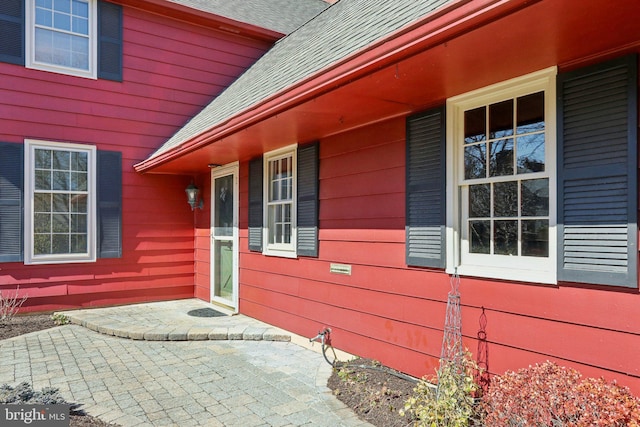 entrance to property featuring covered porch and a shingled roof