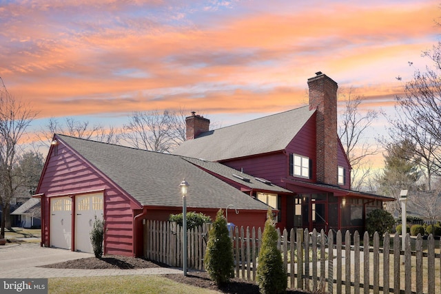 view of front facade with a fenced front yard, roof with shingles, and a chimney