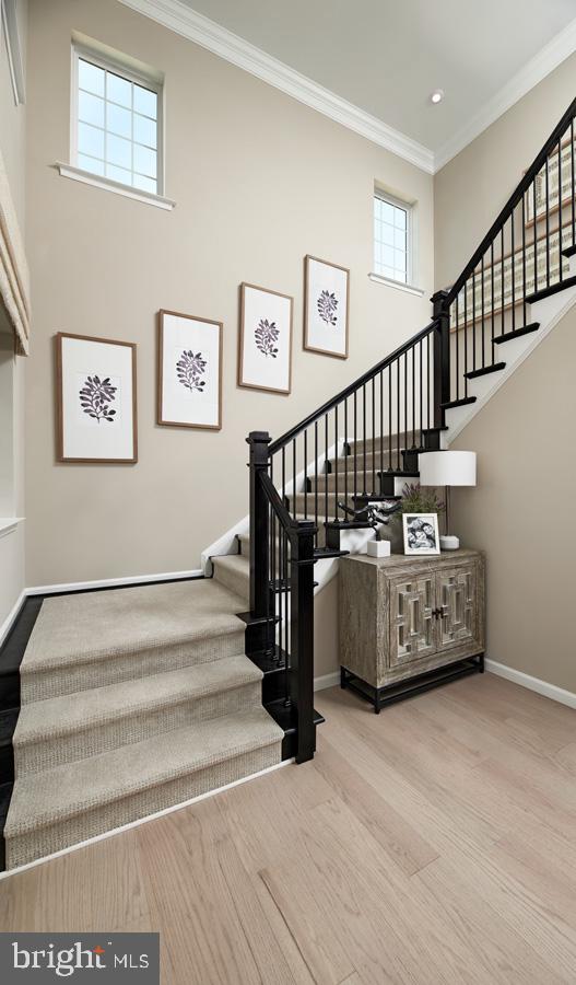 stairs with recessed lighting, wood finished floors, a towering ceiling, baseboards, and crown molding