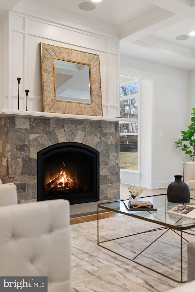 living area featuring beamed ceiling, a fireplace, and coffered ceiling