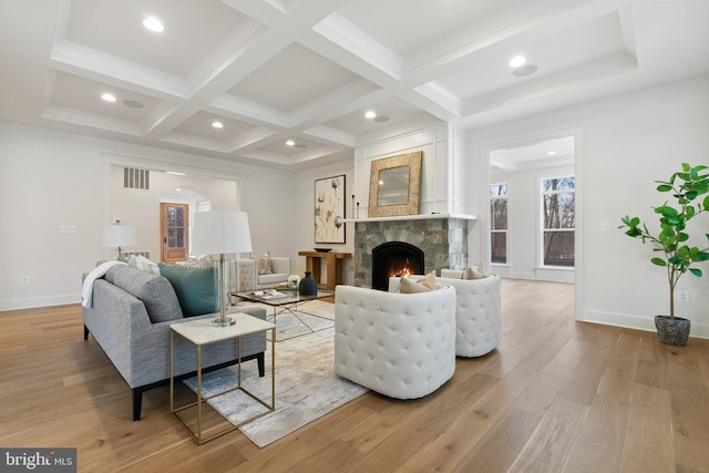 living area with beam ceiling, visible vents, light wood-style floors, a high end fireplace, and coffered ceiling