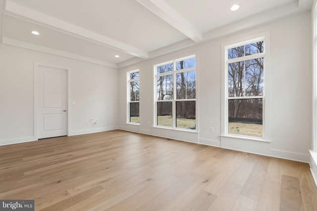 interior space featuring a healthy amount of sunlight, light wood-style floors, baseboards, and beamed ceiling