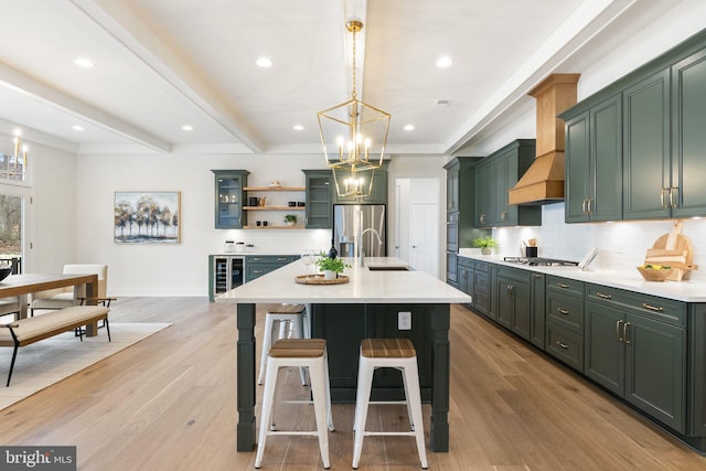 kitchen with green cabinetry, appliances with stainless steel finishes, light countertops, a chandelier, and a sink