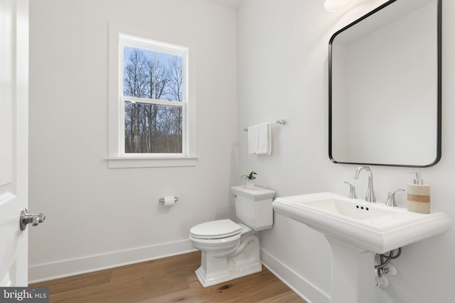 half bathroom featuring wood finished floors, toilet, and baseboards