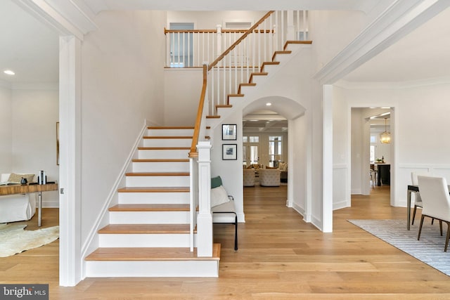 stairs featuring arched walkways, ornamental molding, wood finished floors, and recessed lighting