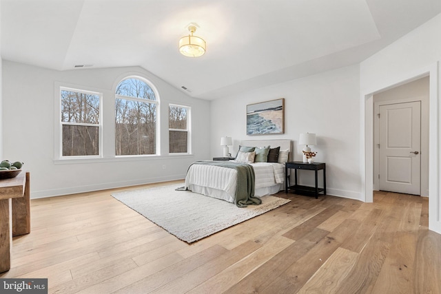 bedroom featuring lofted ceiling, light wood-style floors, baseboards, and visible vents